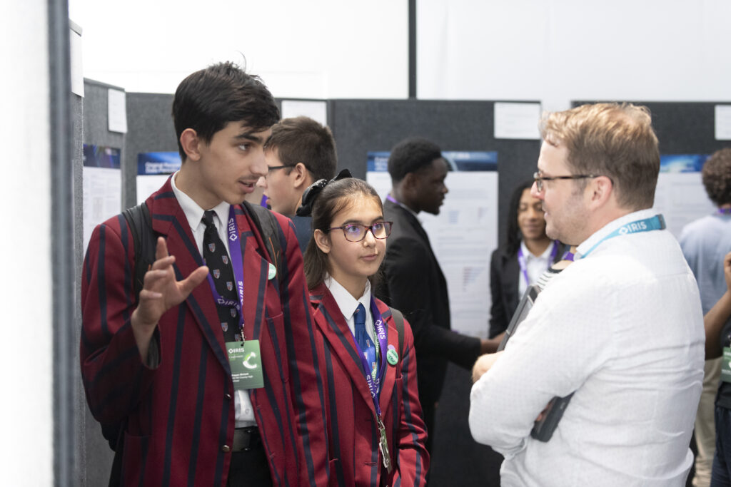 Two students talk about their research to a teacher during London posters sessions