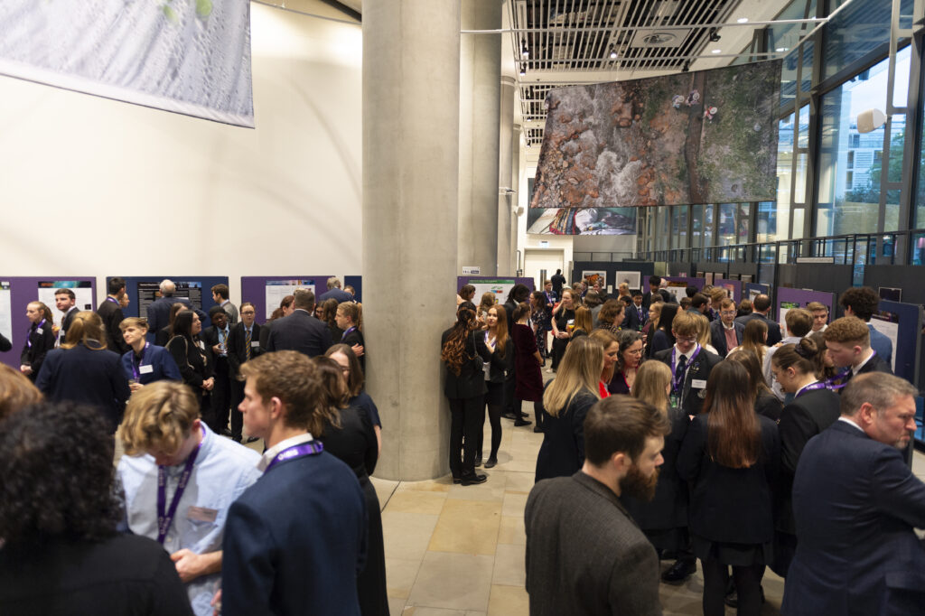 A wide shot of a room filled with students, teachers and partners in discussion.