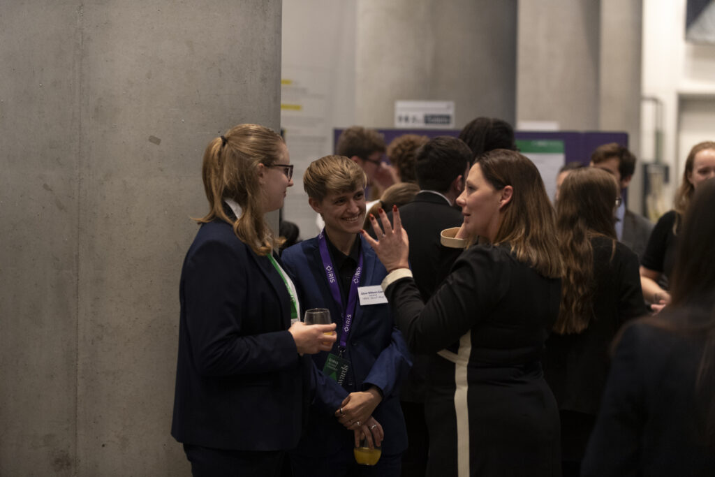 Students and staff smiling and talking at a formal event