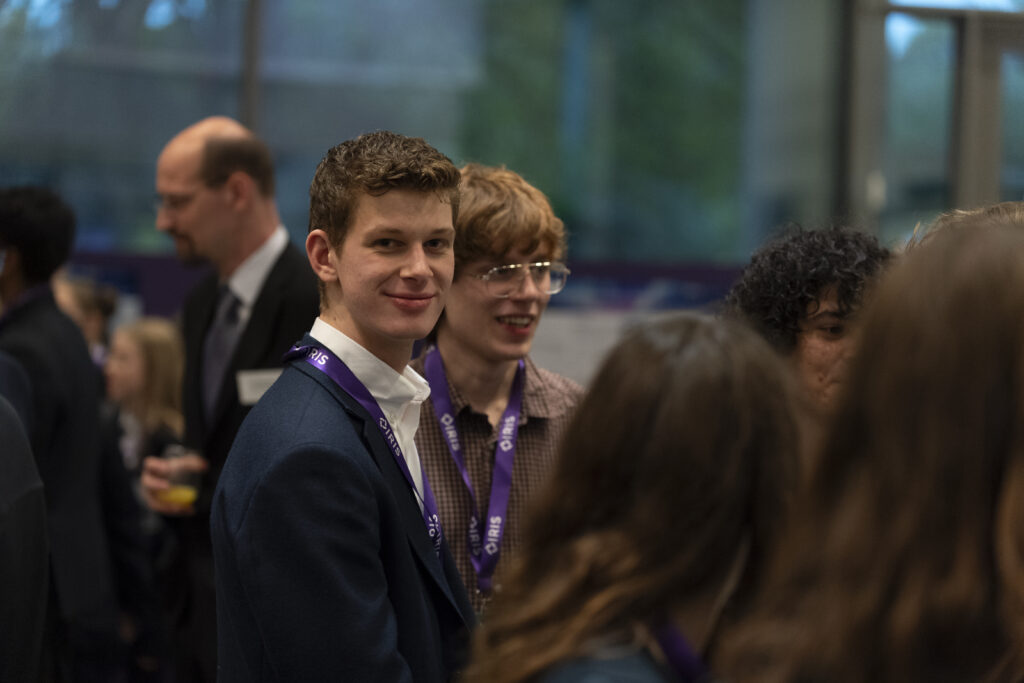 Close up of a group of students talking, with one student looking at the camera and smiling.