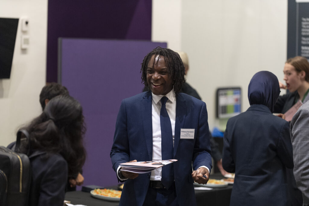 Smiling student in a conference room, talking to another student