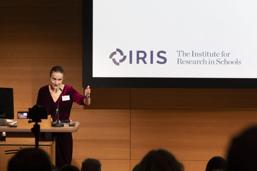 Dr Jo Foster, Director of IRIS, presenting on stage, smiling and gesturing